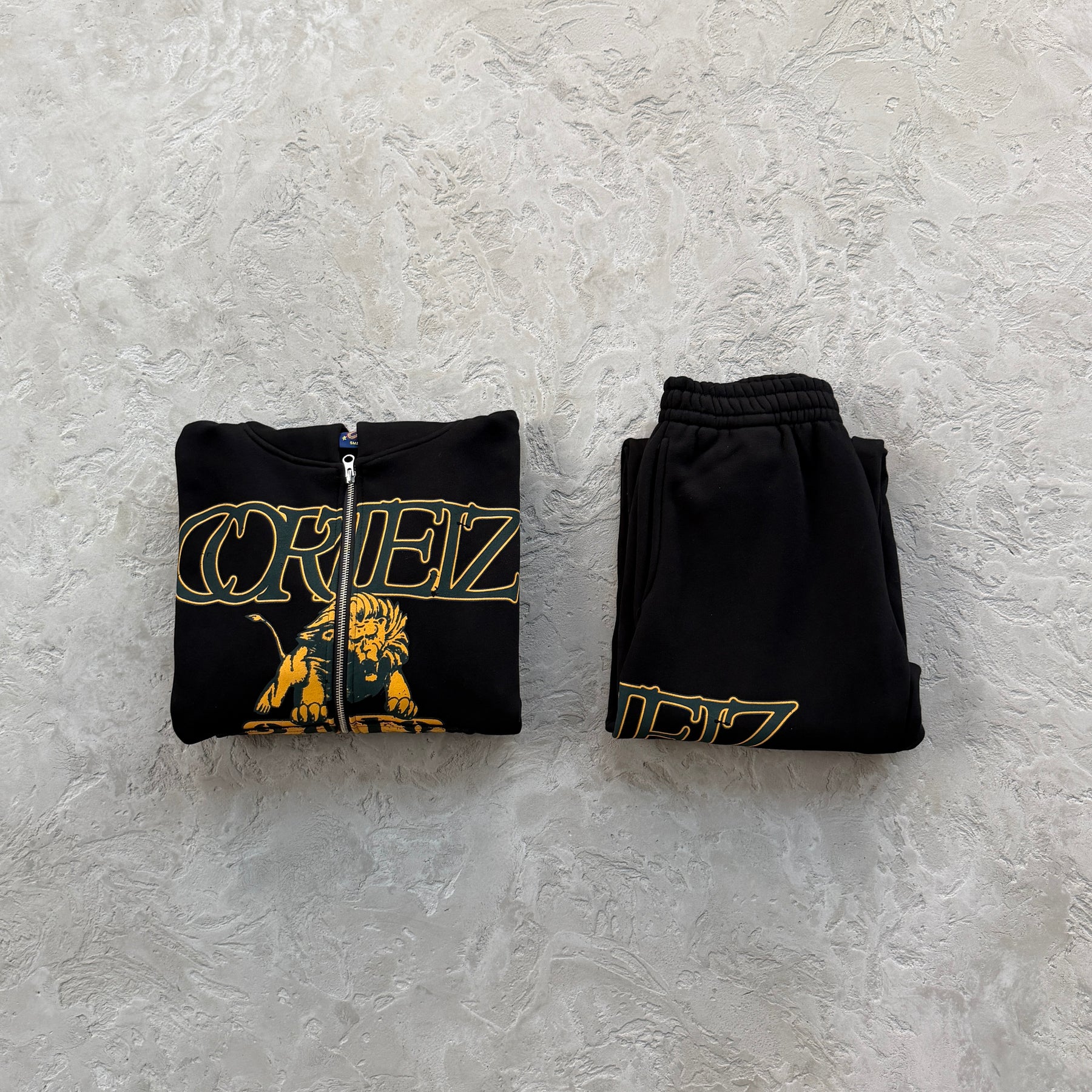 Conjunto Corteiz “Lion Varsity Open Hem Zip”